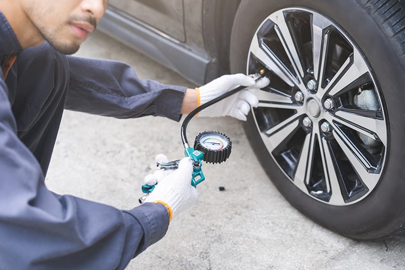 A service expert checking the tire pressure of a car in the service bay